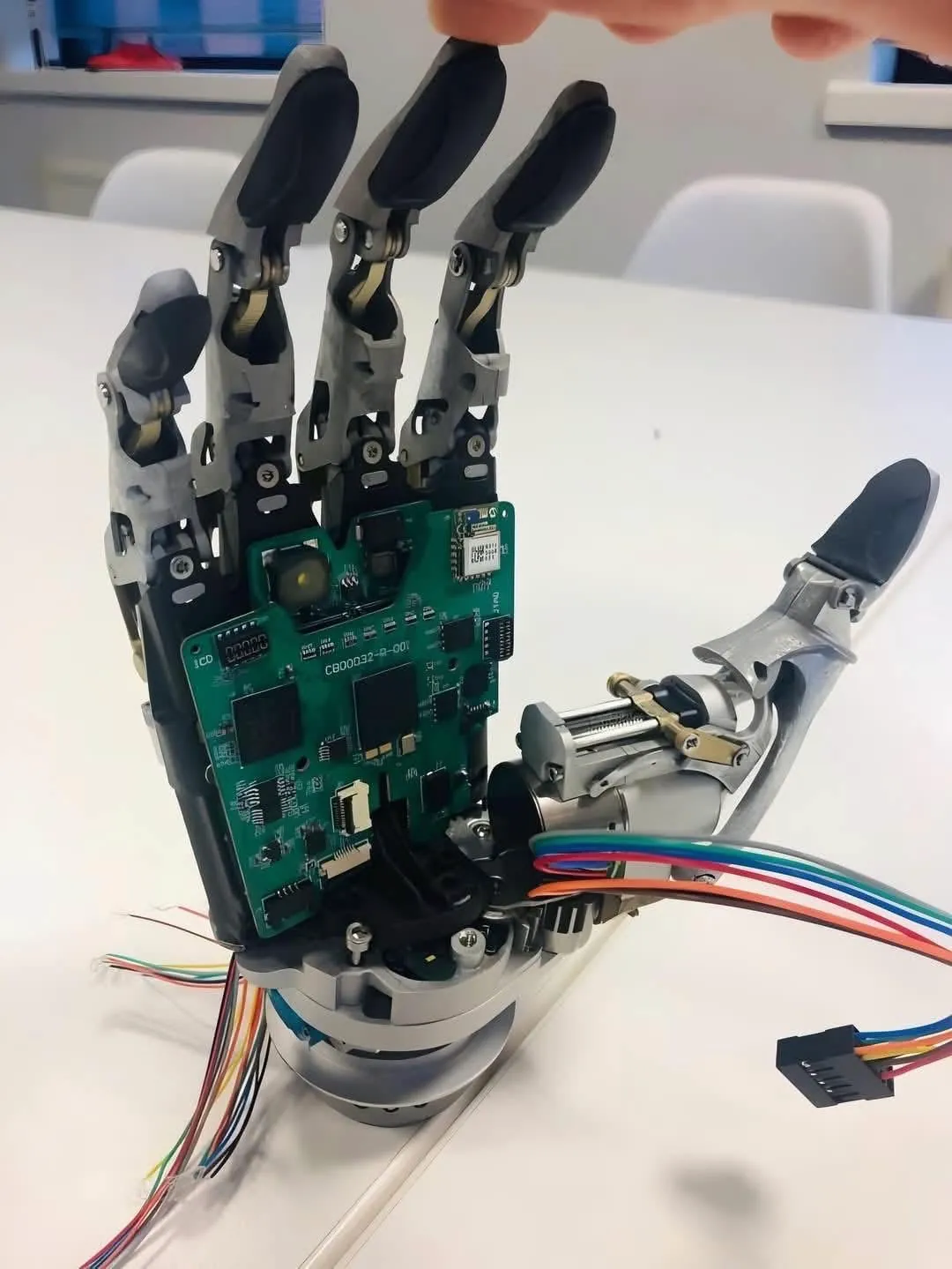 Robotic hand prototype with a green control board and wiring